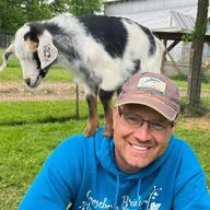 Jeremy Hill in a Gooseberry Bridge Farm sweatshirt, with a young goat standing on his shoulders.